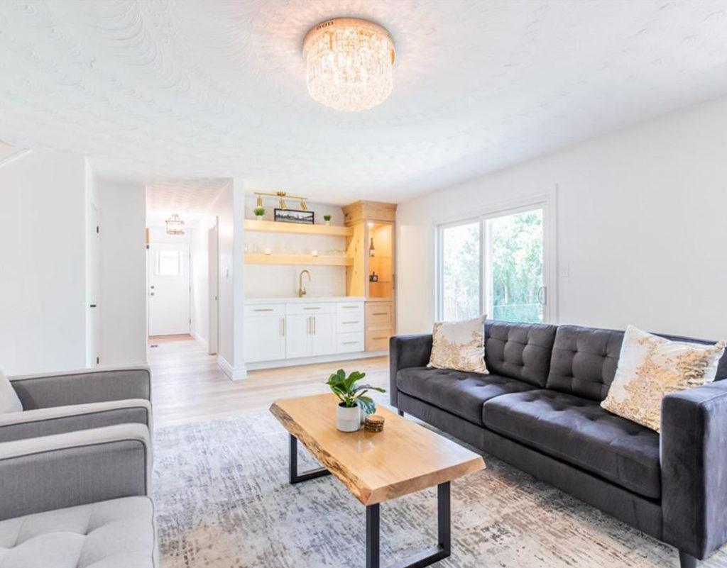 living room with a black sofa and two beige arm chairs