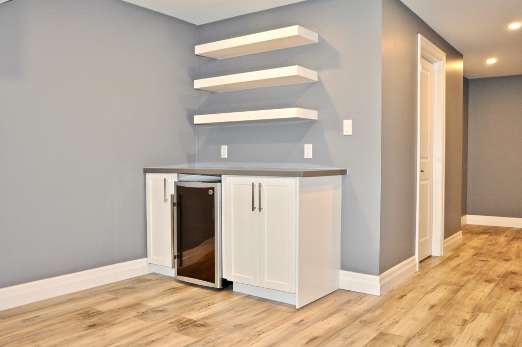 an empty bar in a basement with wooden floors and grey walls