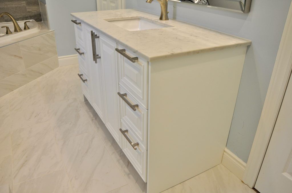 a white bathroom vanity with a white since and brass finishes