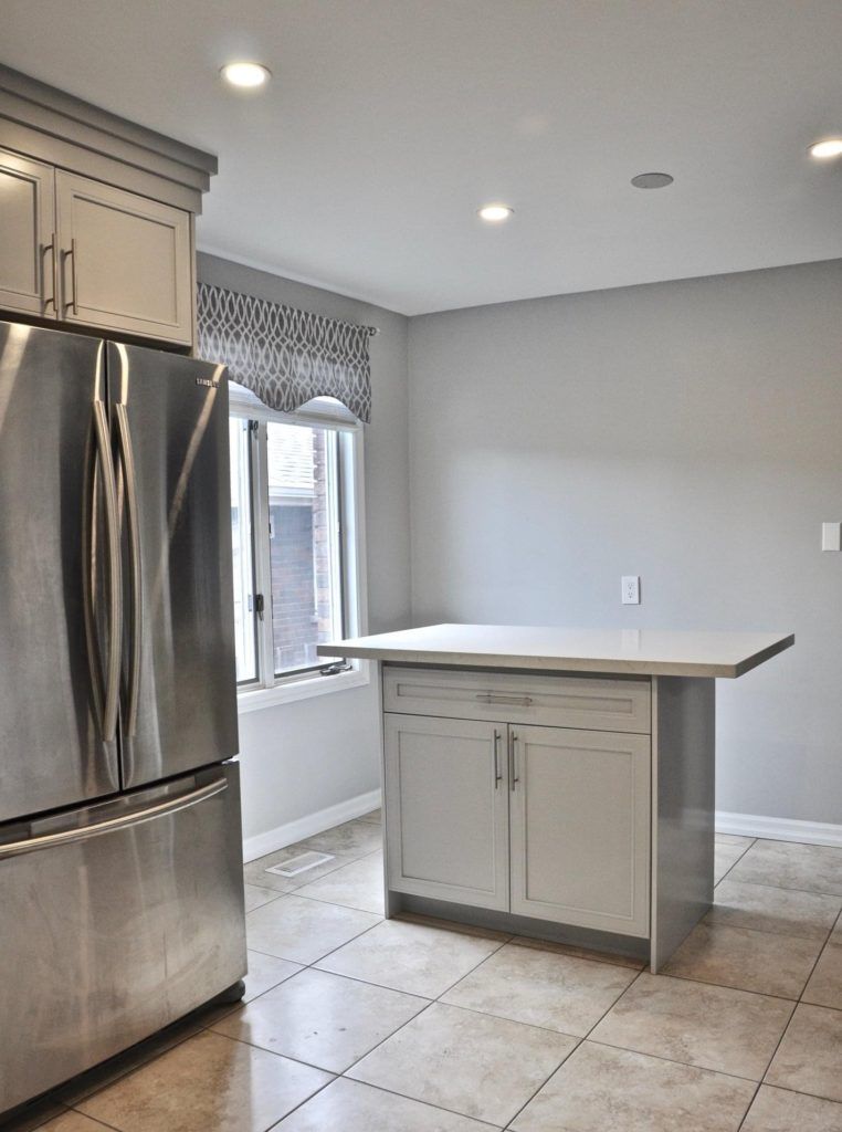 stainless steel fridge next to a grey kitchen island